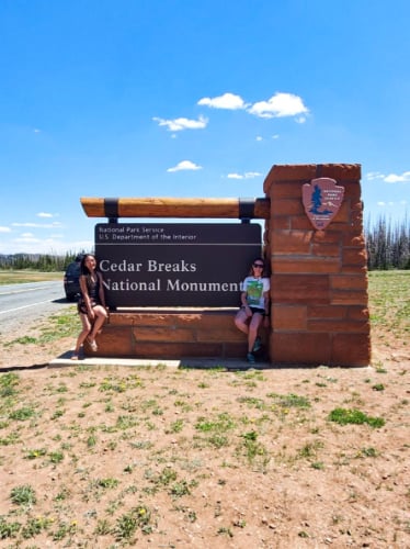 La editora de Travel Lemming, Abigail y su amiga posan en la emblemática señalización del Monumento Nacional Cedar Breaks