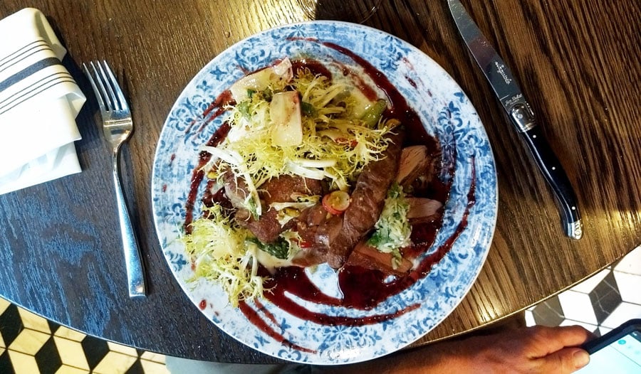 Un plato en un plato en Bistro LeRoux con tenedor y cuchillo al costado