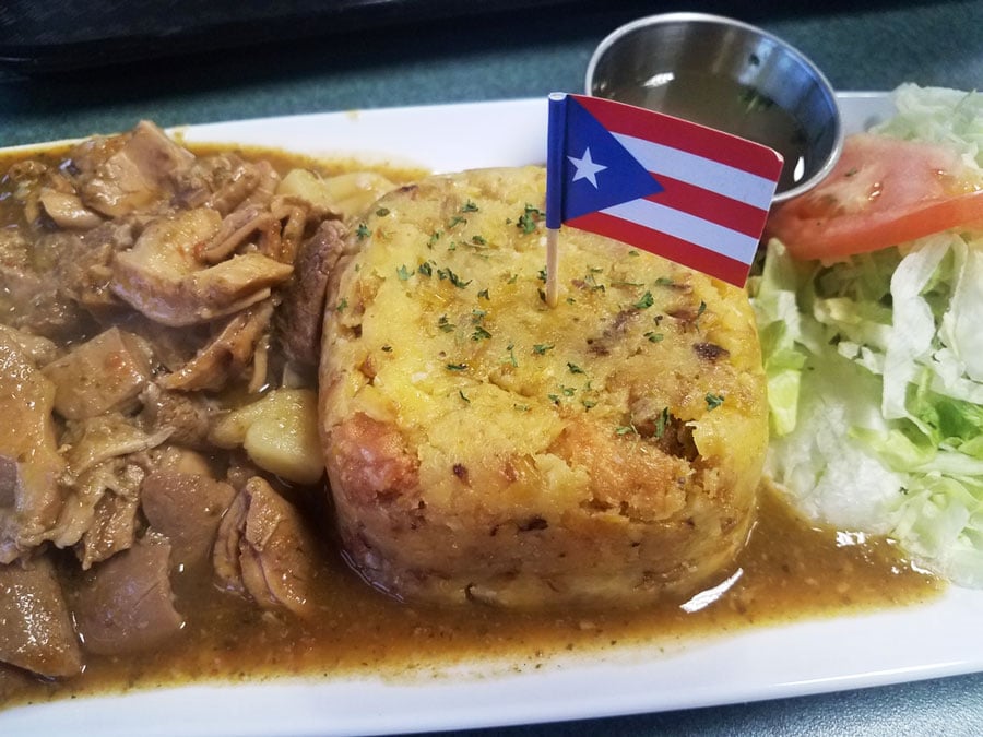 Vista de una carne y un puré de patatas con una bandera de Puerto Rico en un plato