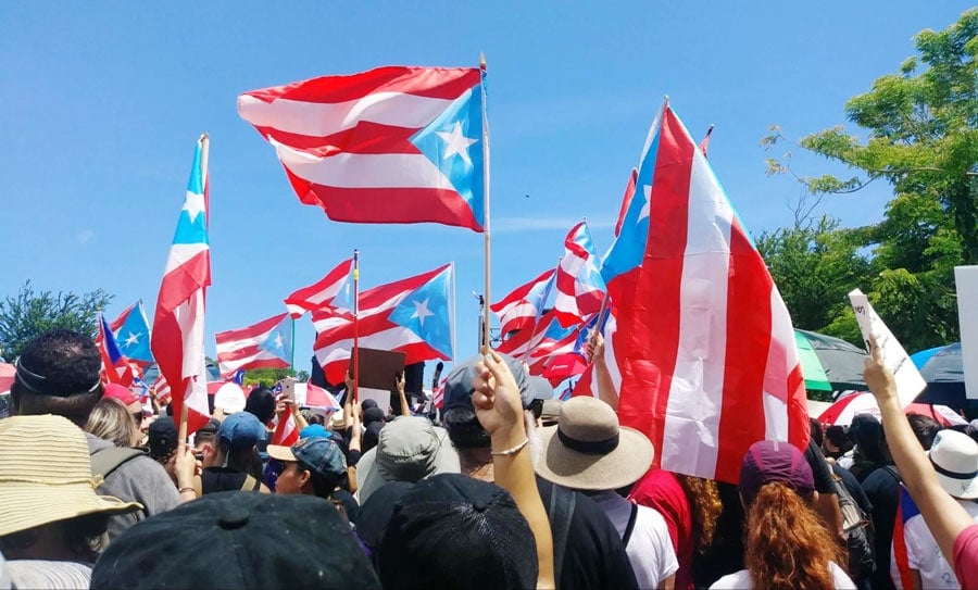 Vista de lugareños izando las banderas de Puerto Rico