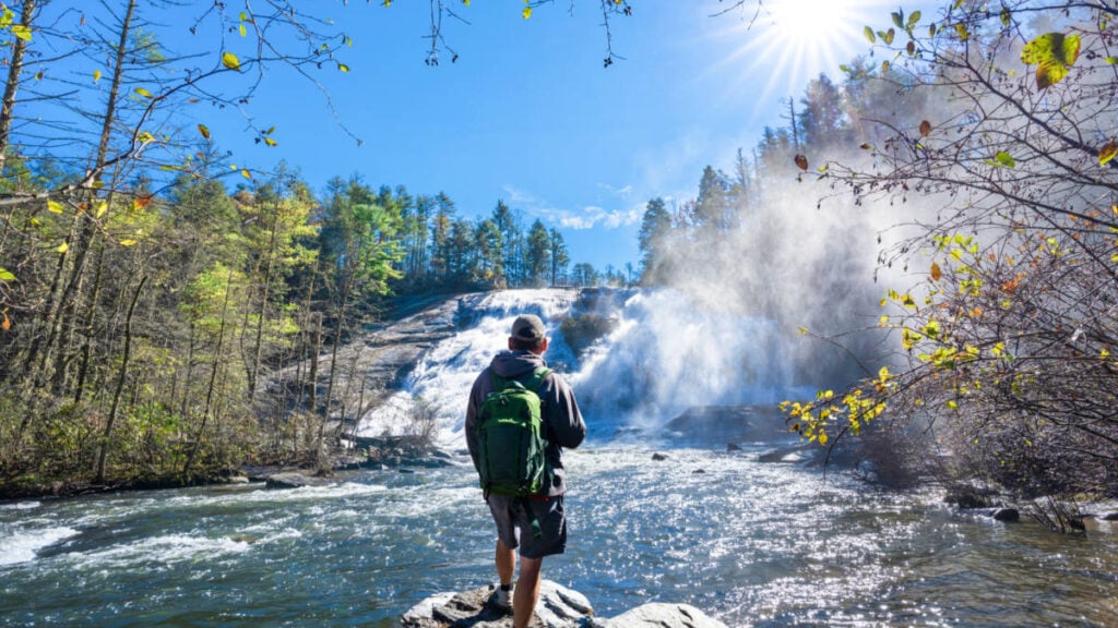 Un hombre admirando High Falls en DuPont State Forest en un día soleado
