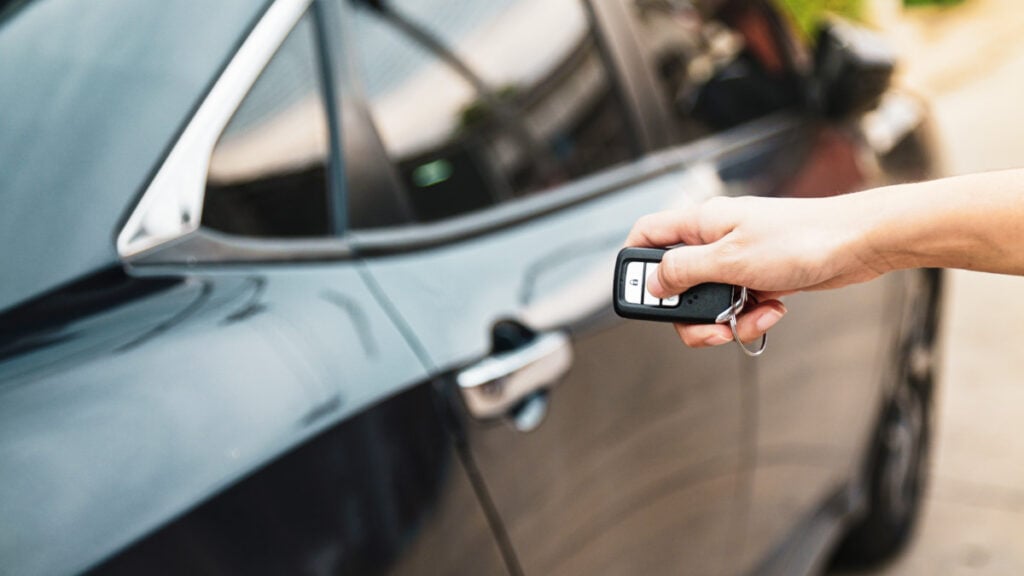 Una mano bloqueando el auto con la llave remota del auto